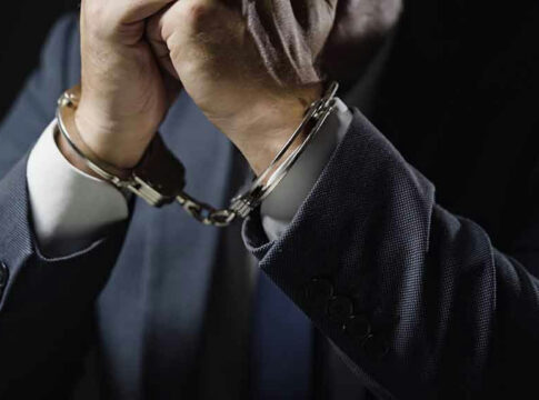 Man in suit wearing handcuffs.