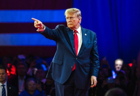 Man in suit pointing on a stage.
