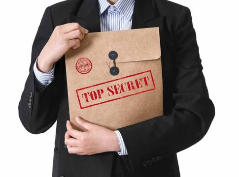Person in suit holding a large brown envelope labeled top secret