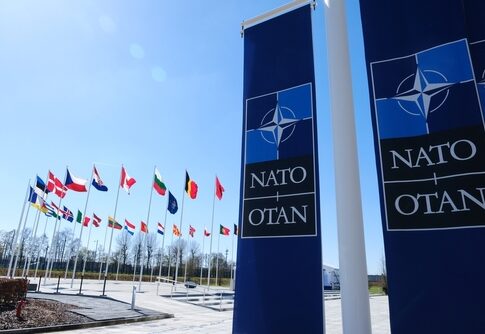 NATO flags displayed at the headquarters under a clear blue sky