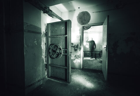 A dark, abandoned room with a mysterious figure in the background